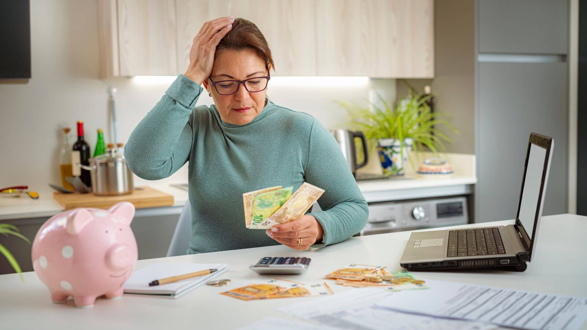 a woman holding a piggy bank in front of a laptop
