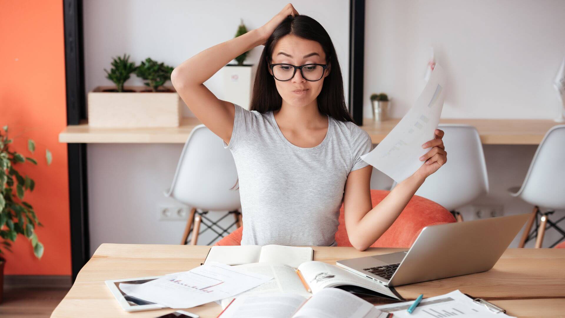 a woman is sitting at a desk with papers and a laptop