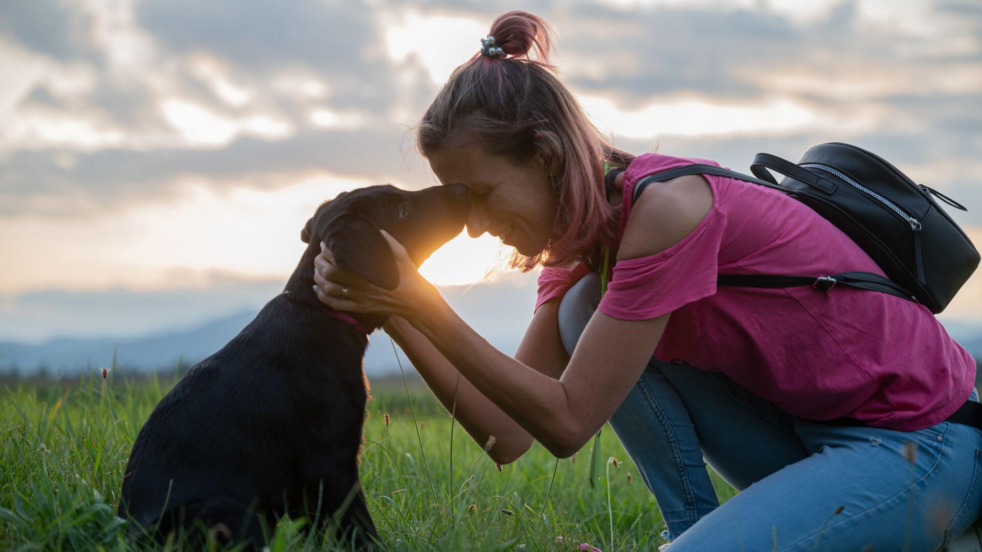 a woman kissing her dog at sunset