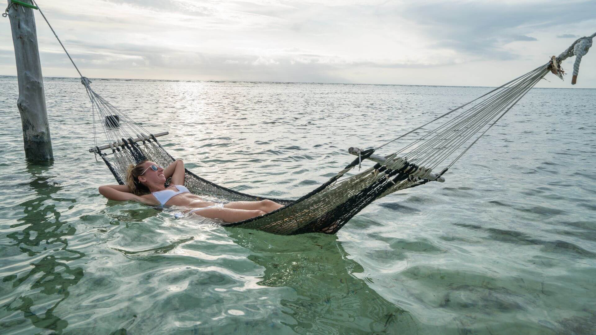 a woman laying in a hammock in the ocean