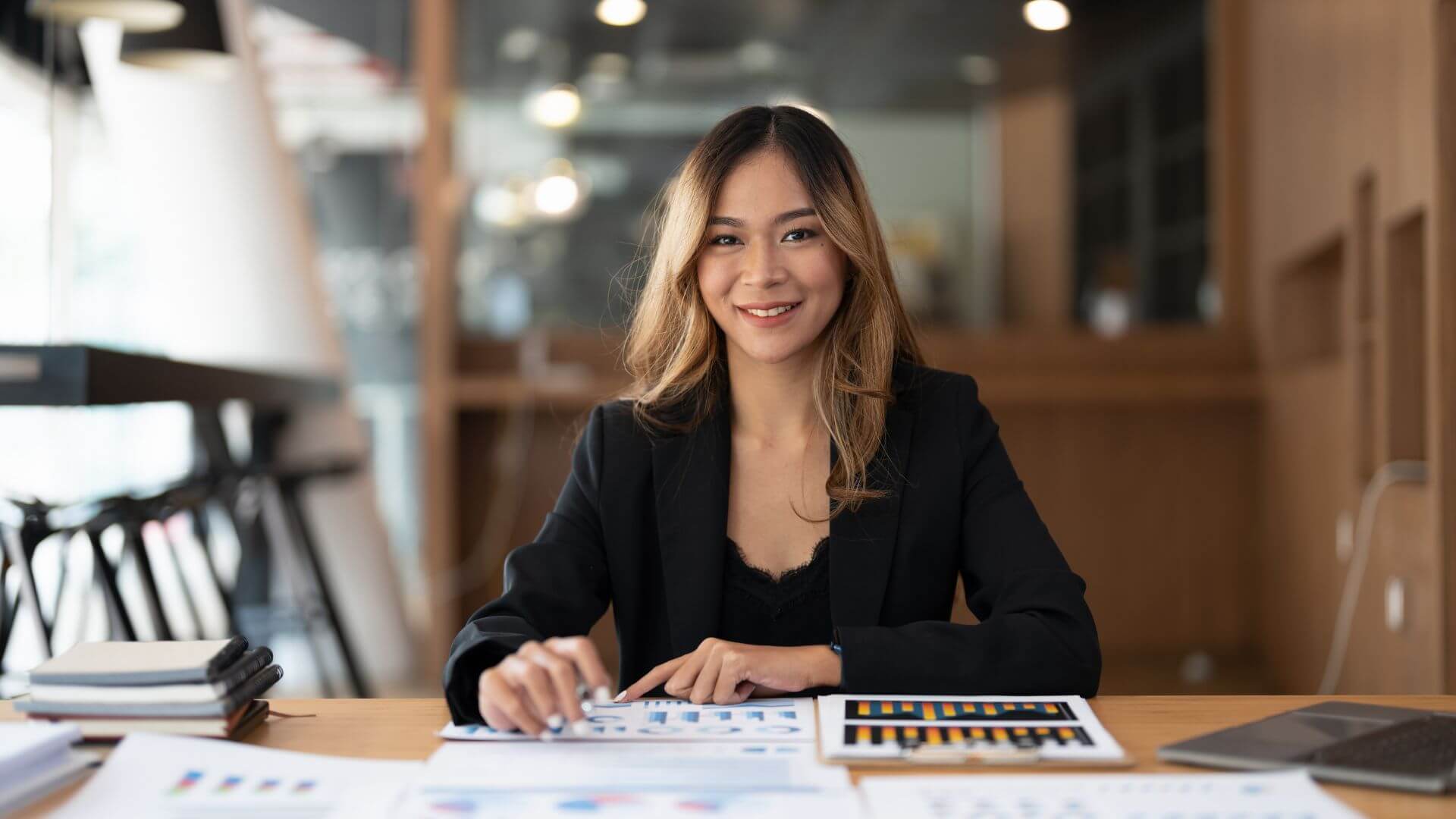 asian businesswoman sitting at a desk with papers and graphs