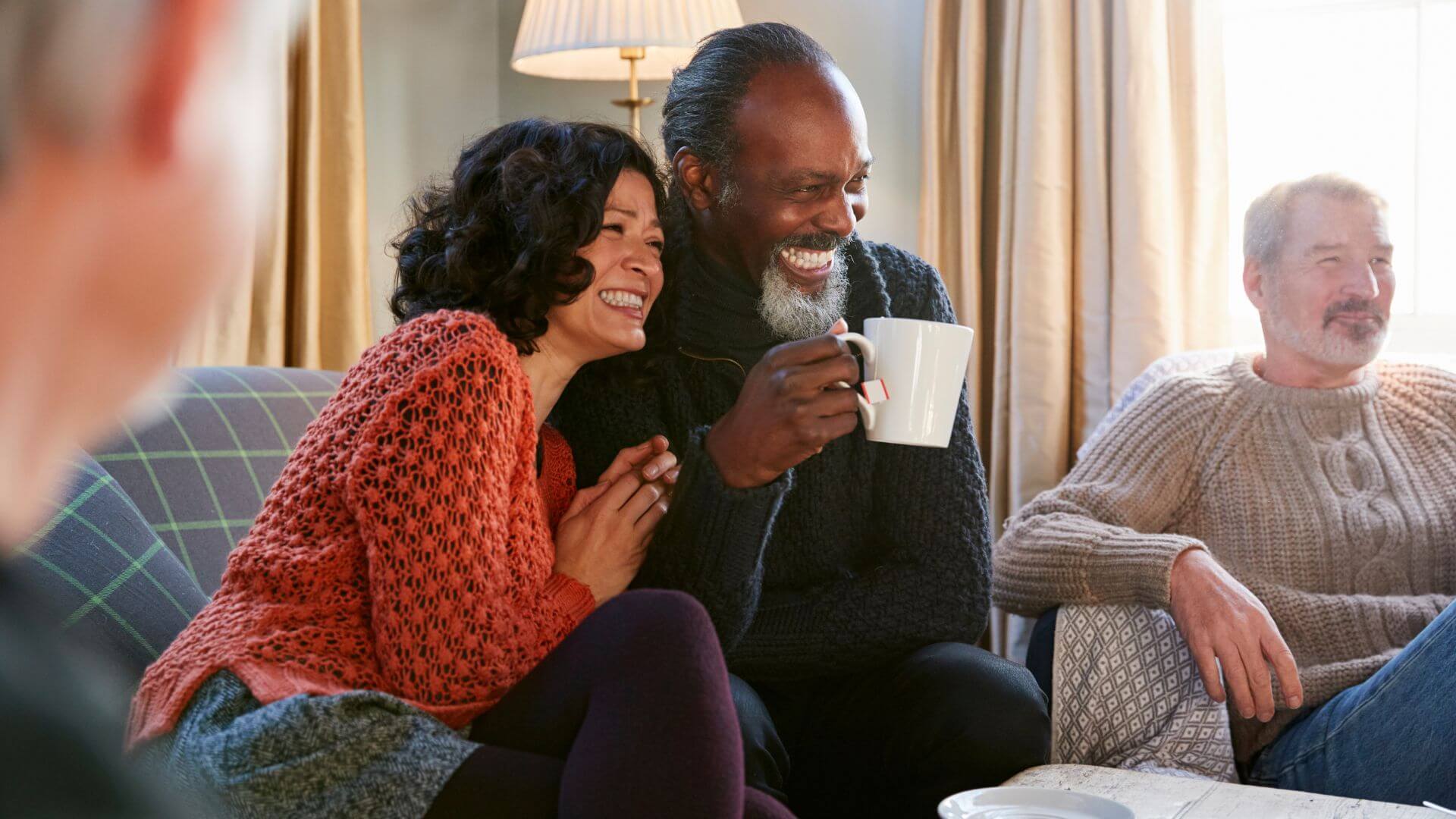 a group of people sitting on a couch with a cup of coffee