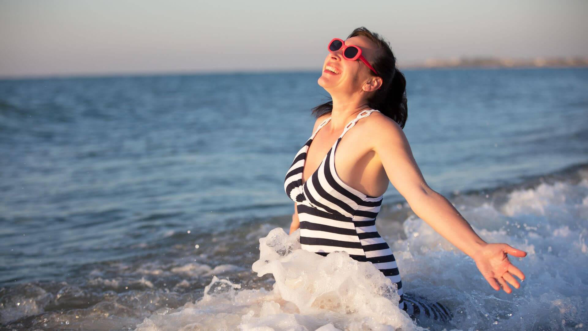 a woman in a striped swimsuit in the ocean