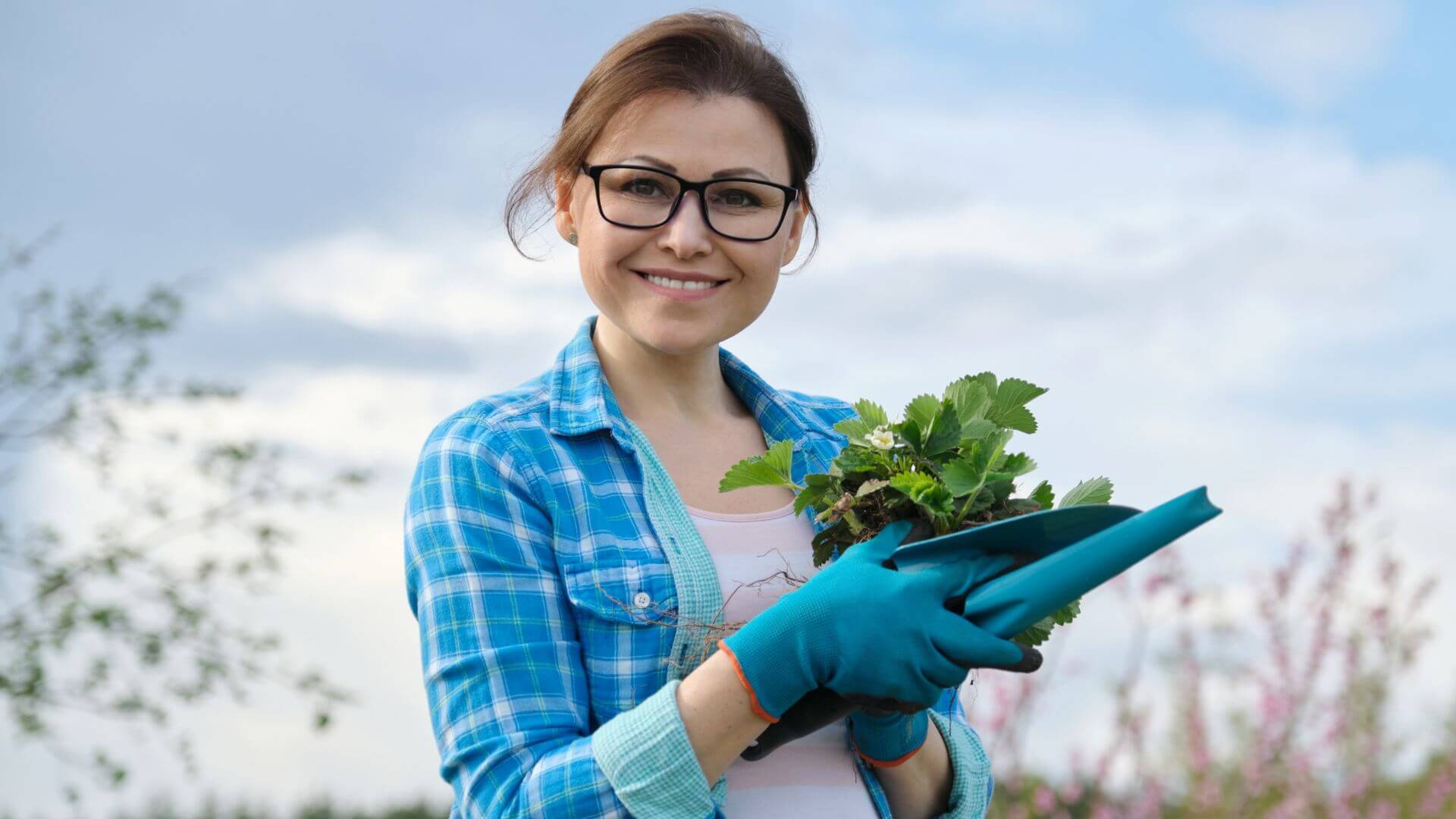 a woman in glasses is holding a plant in her hands