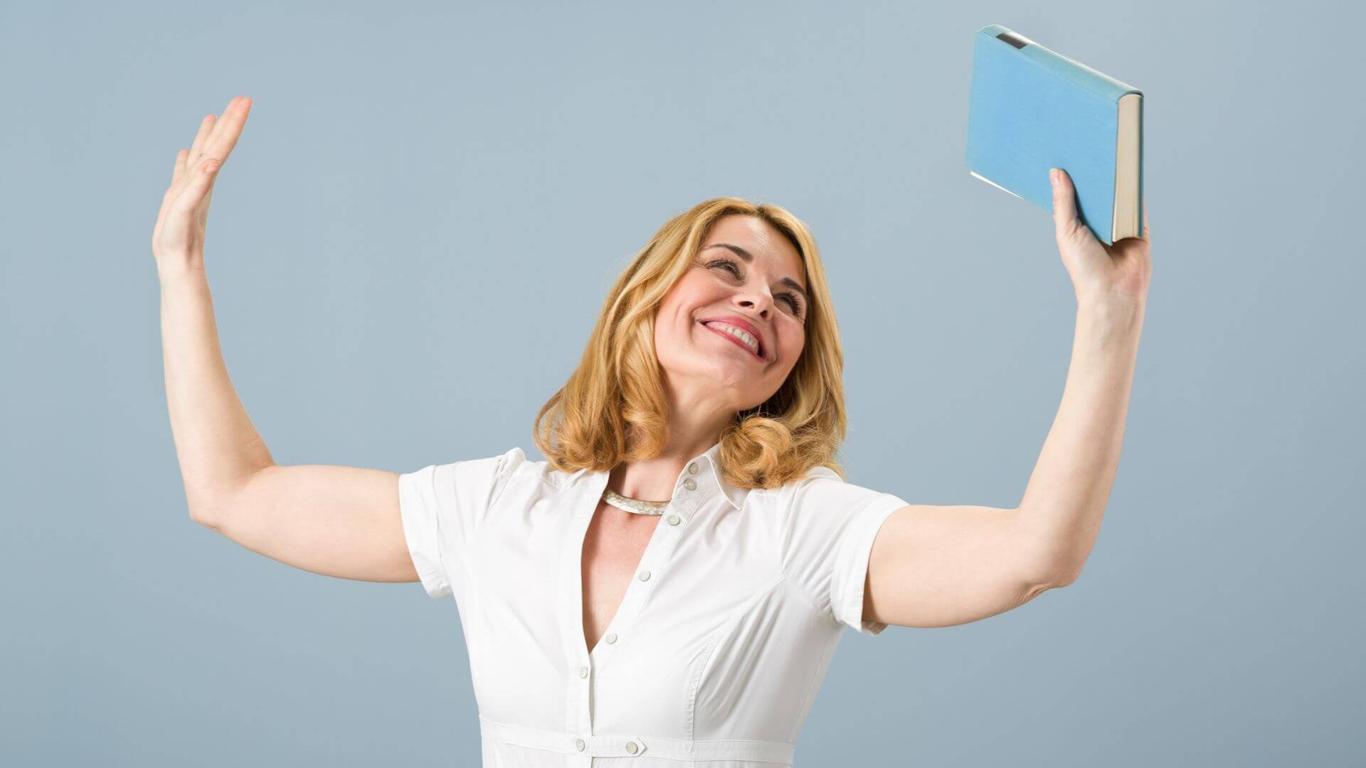 a woman is holding a book up in the air
