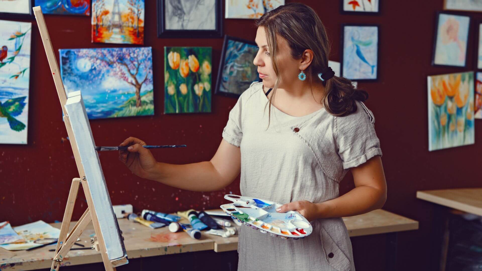 a woman is painting on an easel in an art studio
