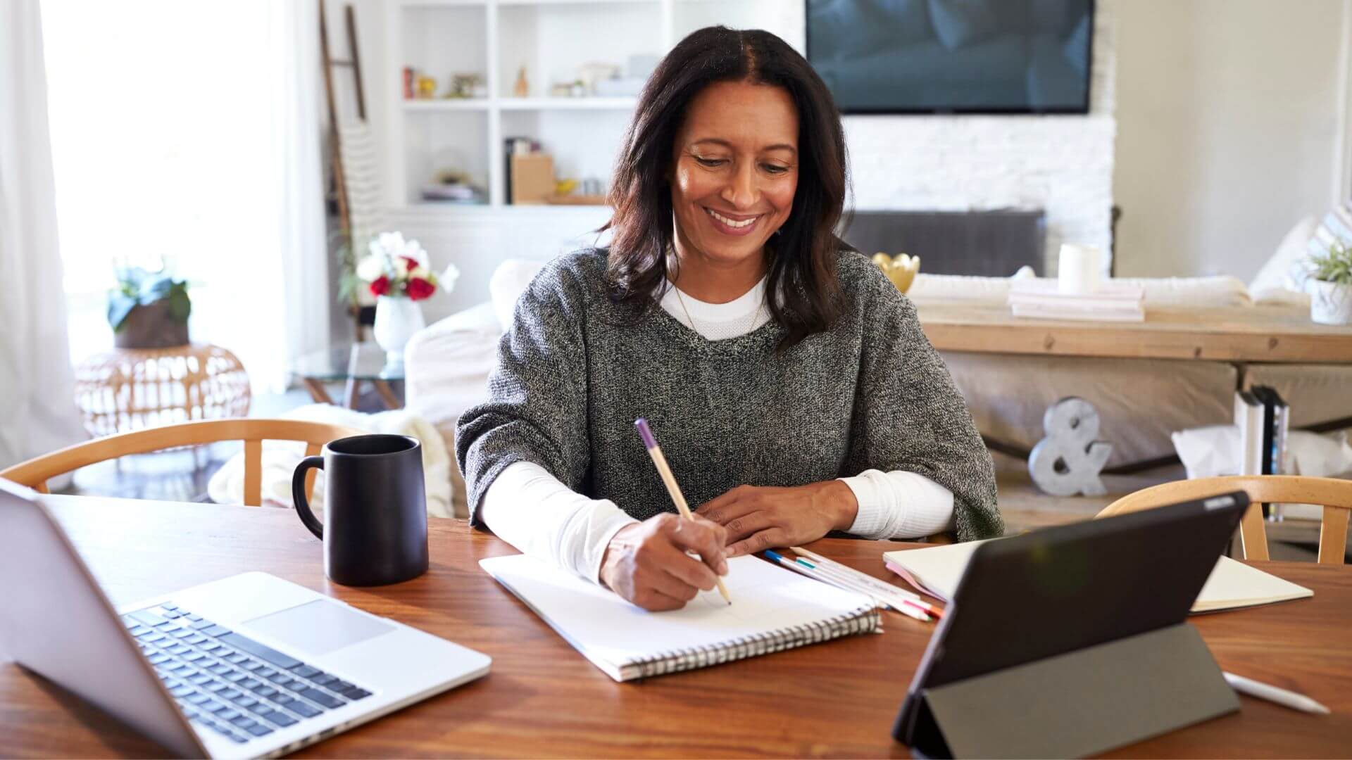 a woman sitting at a table with a laptop and a pen