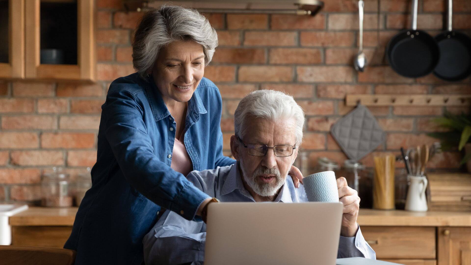 an older couple using a laptop in the kitchen